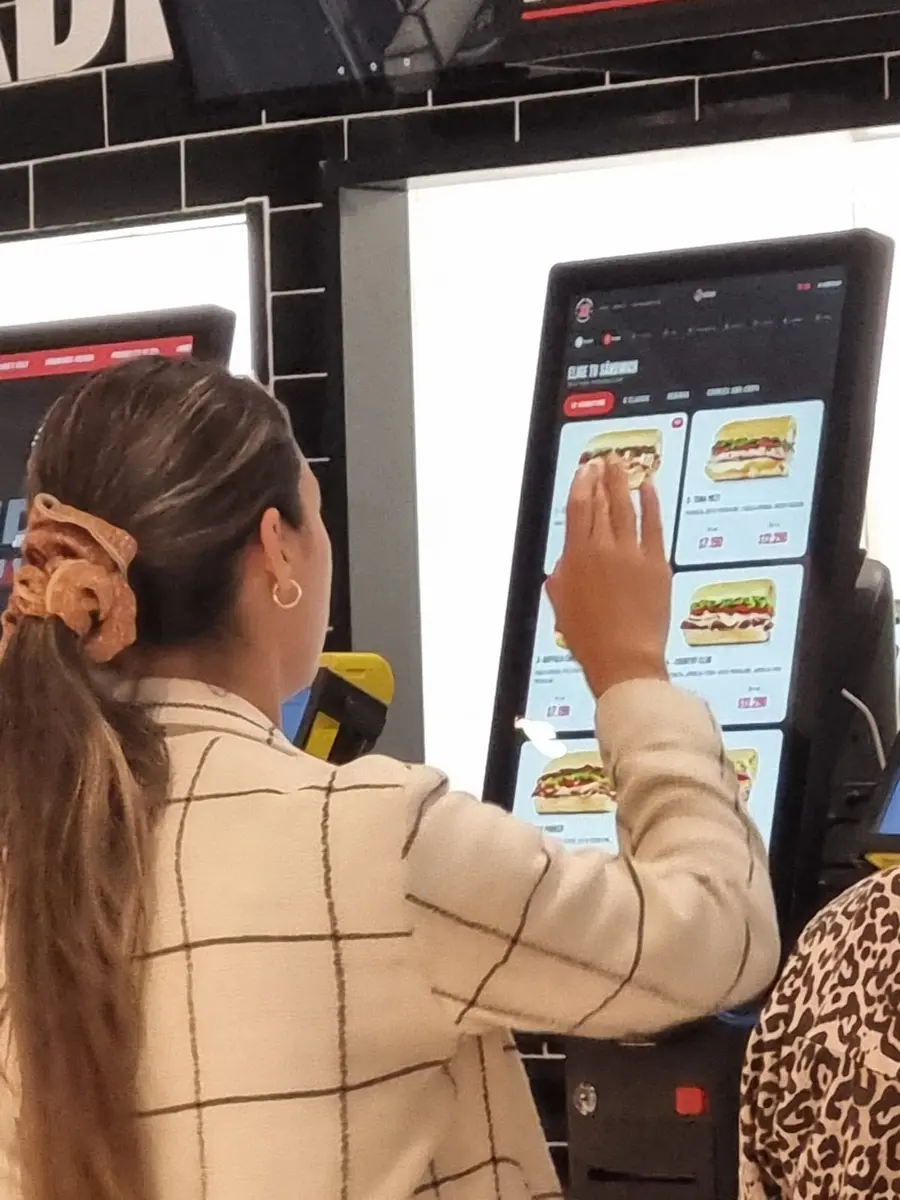 Cliente seleccionando productos en la pantalla del tótem